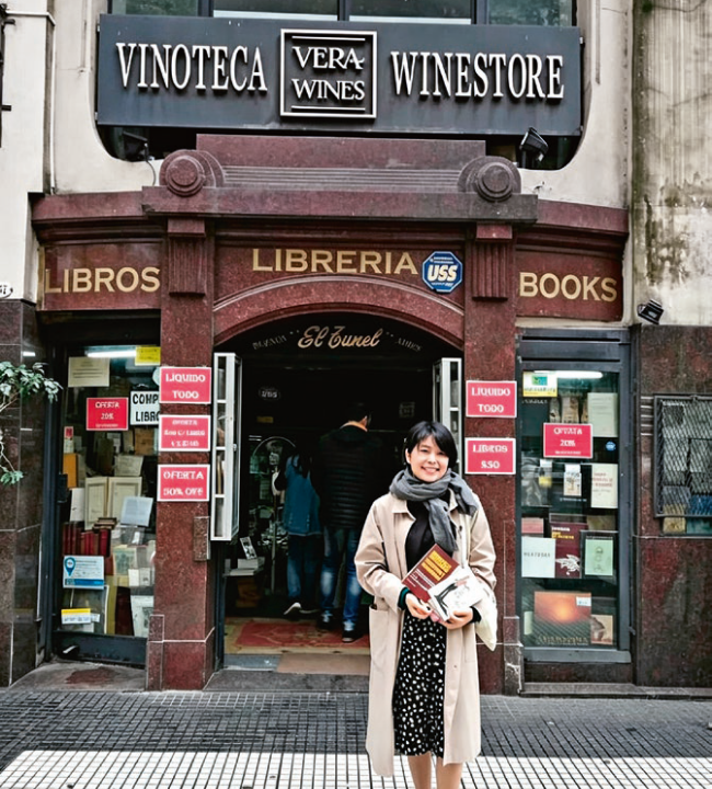 Lu Min sostiene libros de Manuel Puig frente a una librería durante su visita a Buenos Aires en 2019.
