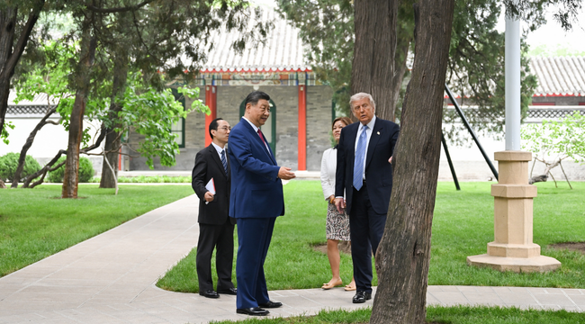 Xi Jinping conversa con Donald Trump durante un recorrido por un jardín, acompañados por integrantes de sus delegaciones.